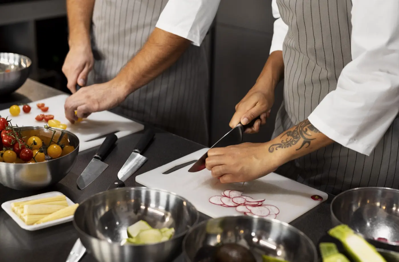 Élèves en tablier qui découpent des légumes en cuisine